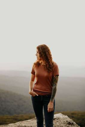 Red haired woman standing on the edge of a cliff. This woman illustrates the adults to come for trauma treatment with Sacred Circle Holistic Healing in Kansas City, Kansas. 