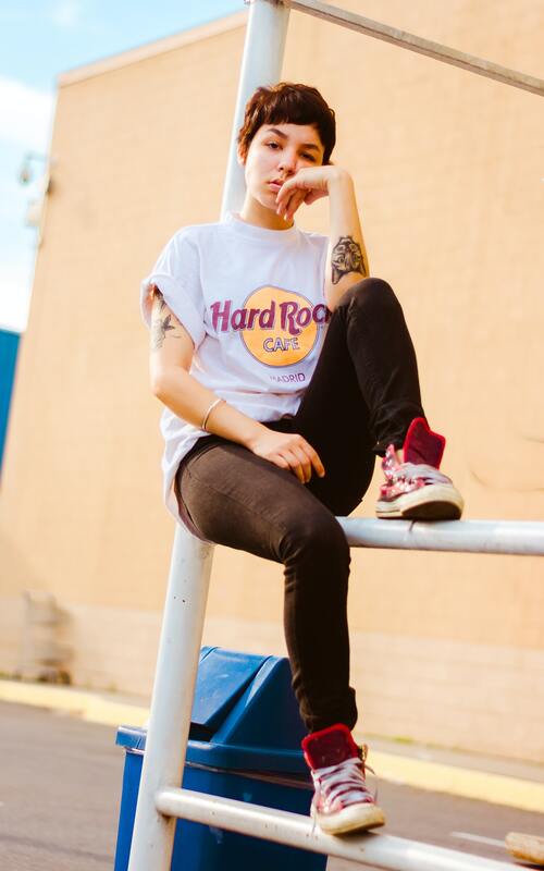 Young woman with short hair and tattoos sitting on a metal pole. This illustrates that highly sensitive people come from all walks of life. Maggie Jones Boyle specializes in therapy for highly sensitive adults in Lawrence and Kansas City. 