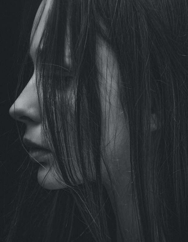 Black and white portrait of the side profile of a woman's face with dark hair hanging between her face and the camera. This represents the pain of grief. Maggie Jones Boyle specializes in providing online counseling for the bereaved in Kansas. 