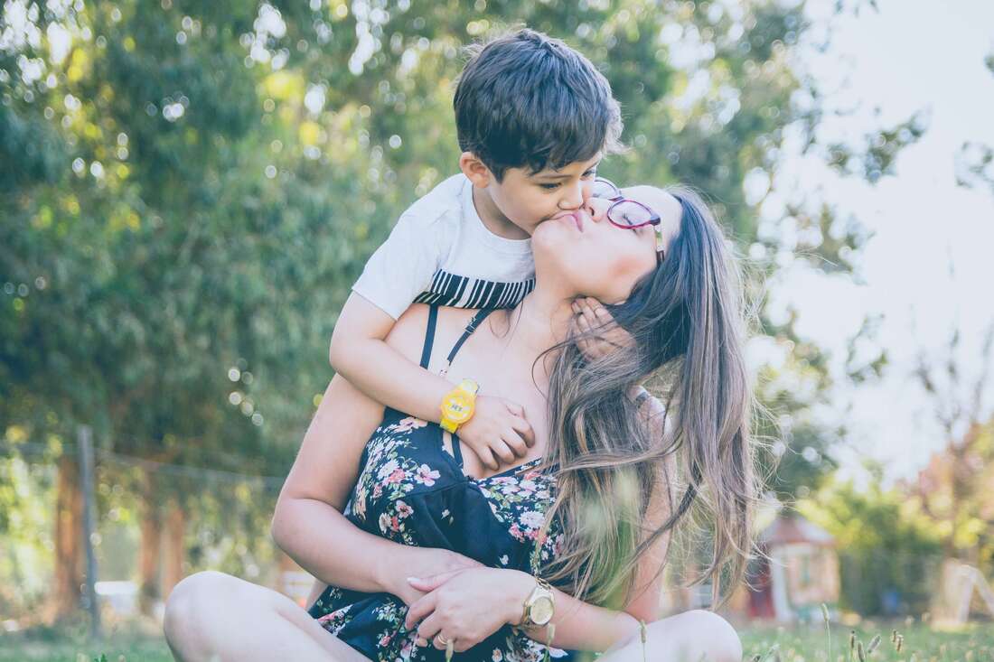 Mother kissing her son representing how going to therapy or counseling for childhood trauma can stop the transmission of intergenerational trauma.