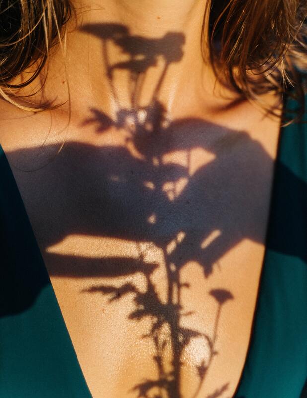Photo of a shadow of hands holding flowers in front of a woman's chest. This represents that we each of an inner child that needs to be cared for. Sacred Circle Holistic Healing offers online therapy in Kansas for people struggling with anxiety and low self-esteem.