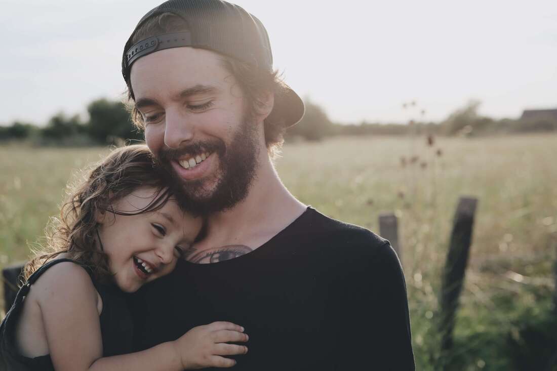 A father and child laughing which represents a healthy family system. Maggie Jones Boyle specializes in working with adult survivors of childhood trauma in Kansas.