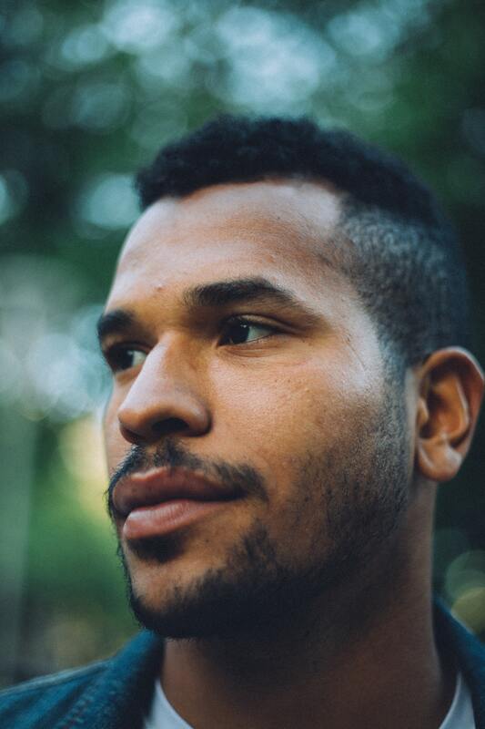 Close up portrait of a young Black man who is looking off camera. This illustrates that Sacred Circle Holistic Healing helps young adults heal low self-esteem and anxiety through online therapy services in Kansas.
