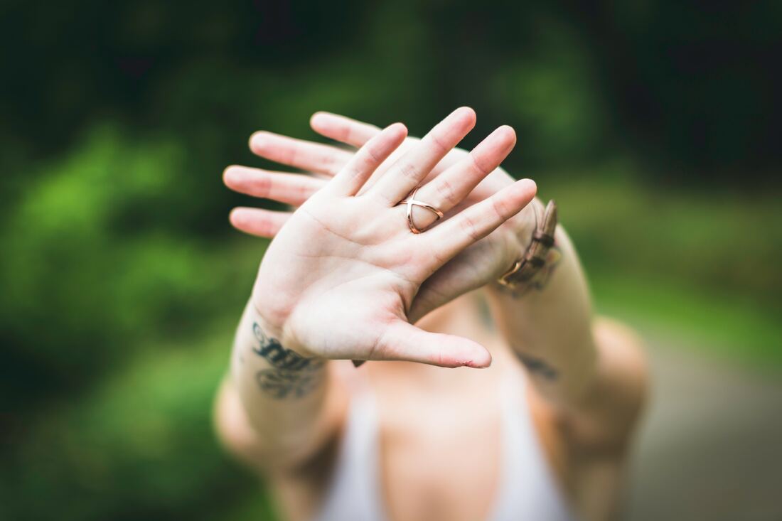 A woman putting her hands together in front of her face representing the importance of boundaries. Sacred Circle Holistic Healing provides online therapy for boundaries and people-pleasing.