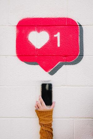 A hand holding an iPhone in front of a brick wall with an Instagram 