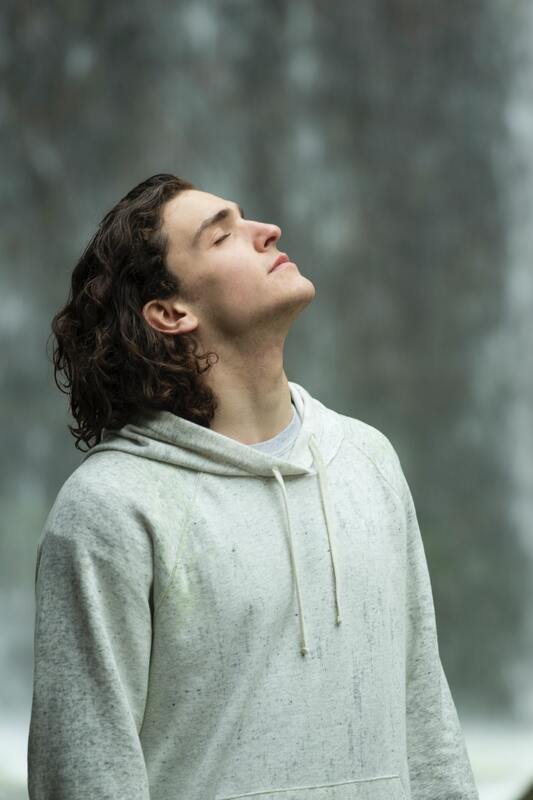 Young man with long, brown hair tipping head up toward the sky, eyes closed. This represents that Sacred Circle Holistic Healing offers online therapy in Kansas and helps young people build emotional intelligence. 