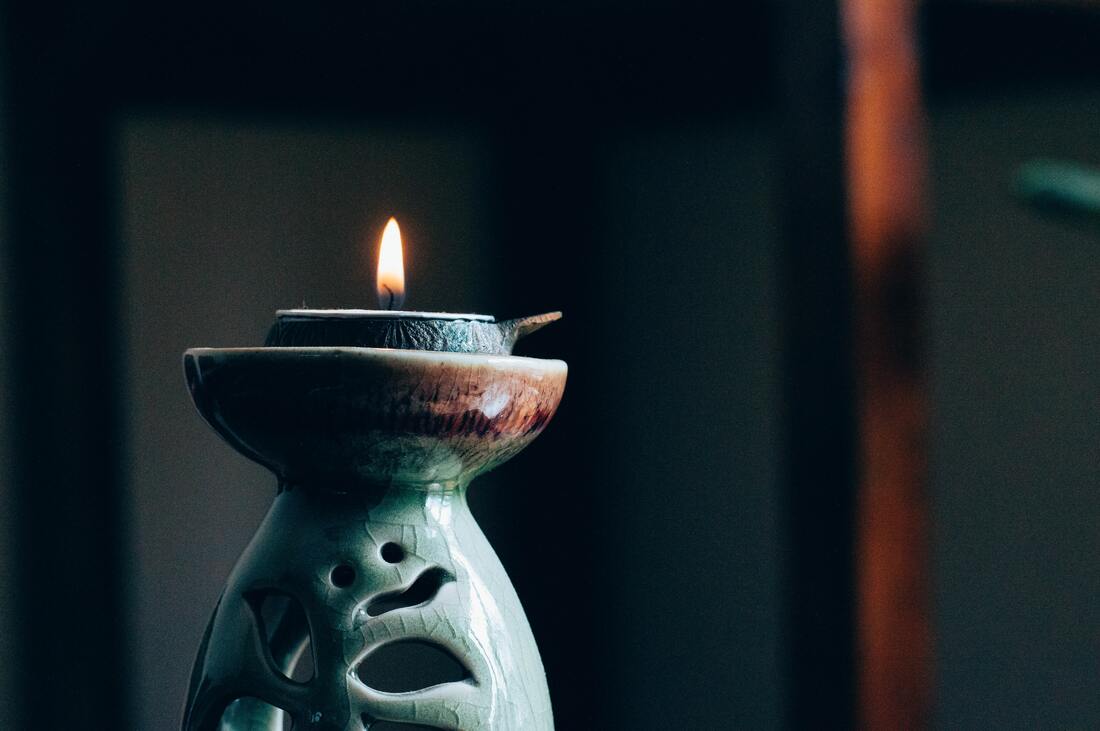 Flame burning on an incense cone sitting on a light blue ceramic incense holder. This represents a form of meditation and that Sacred Circle Holistic Healing offer mindfulness-based holistic therapy online in Kansas.