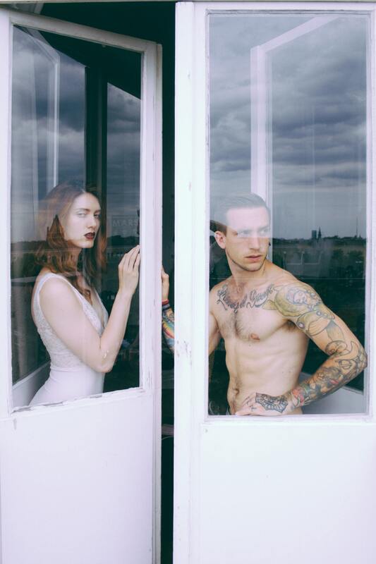 Photo of a woman and a man both behind separate panes of glass, representing relational boundaries. Sacred Circle Holistic Healing offers online therapy for adults throughout Kansas.