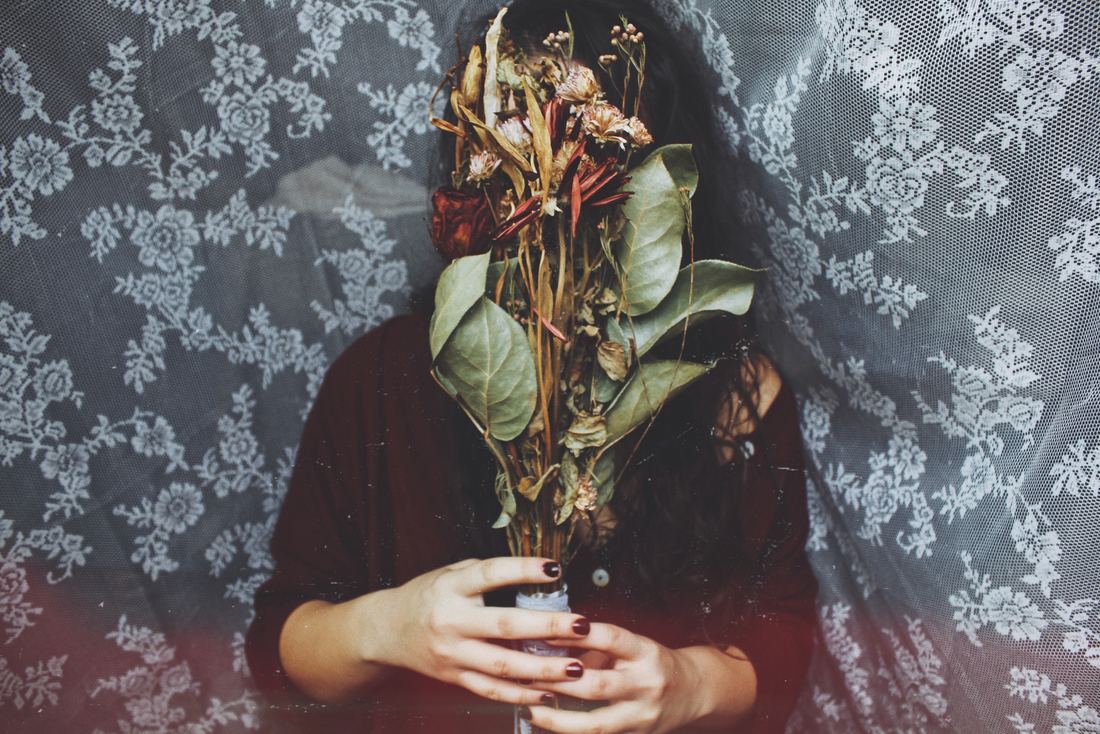 Woman hiding face behind bouquet. This illustrates how the symbolism of the Rising in Evolutionary Astrology represents how we present in social situations.