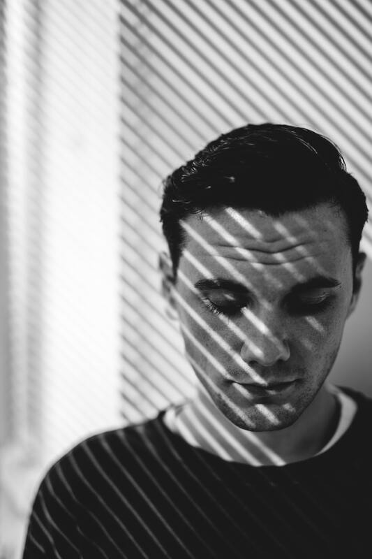 Black and white photo of a young man looking down. This represents that Sacred Circle Holistic healing provides online counseling services in Kansas for young adults.