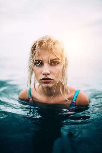 Young woman with blonde hair swimming water represents someone who has experience childhood trauma. I offer treatment for childhood trauma, anxiety, low self-esteem, and codependency for adults in Kansas and Florida.
