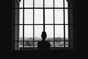 Silohette of a woman looking out a large window. This respresents how grief can be lonely. Maggie Jones Boyle, LPC offers grief counseling in Lawrence, Kansas.