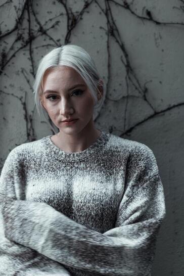 Photo of a young woman in a gray sweater representing someone who is attending therapy for childhood trauma. I offer counseling for anxiety, low self-esteem, and childhood trauma online for residents of Kansas and Florida.