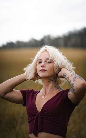 Young woman with blonde hair looking into the camera representing someone who has entered therapy with Sacred Circle Holistic Healing in Lawrence, Kansas for online therapy addressing childhood trauma, anxiey, and self-worth. 
