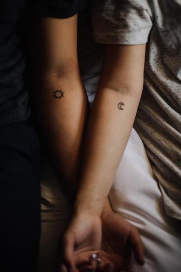 Two arms holding hands, one with a moon tattoo and one with a sun tattoo. This illustrates that I offer evolutionary astrology readings.