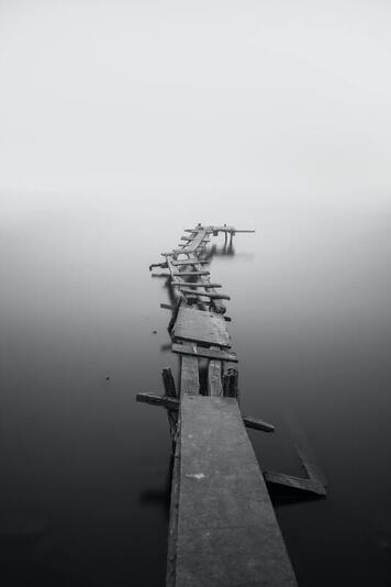 Black and white photo of a wooden dock, broken into pieces. This illustrates how one often feel 