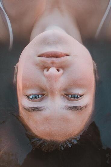 Close of a white woman's face, the rest of her body is submerged under water. This illustrates that Sacred Circle Holistic Healing helps young adults learn how to deal with their emotions through online therapy in Kansas.