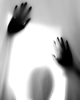 Black and white photo of a figure pressing their hands against fogged glass. This represents how grief can feel like you are trapped in fog. Sacred Circle Holistic Healing offers grief and bereavement counseling in Lawrence, Kansas.