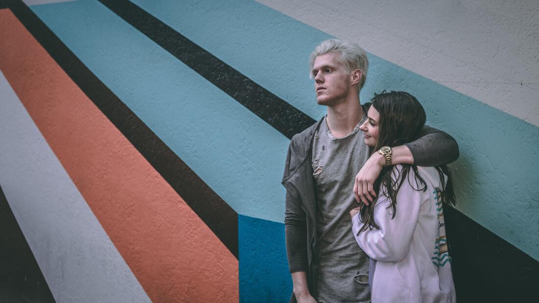 A man and woman standing next to a wall. The man has his arm around the woman and is not smiling. This illustrates and Sacred Circle Holistic Healing in Kansas offers online counseling of recovery from toxic relationships and narcissistic abuse. 
