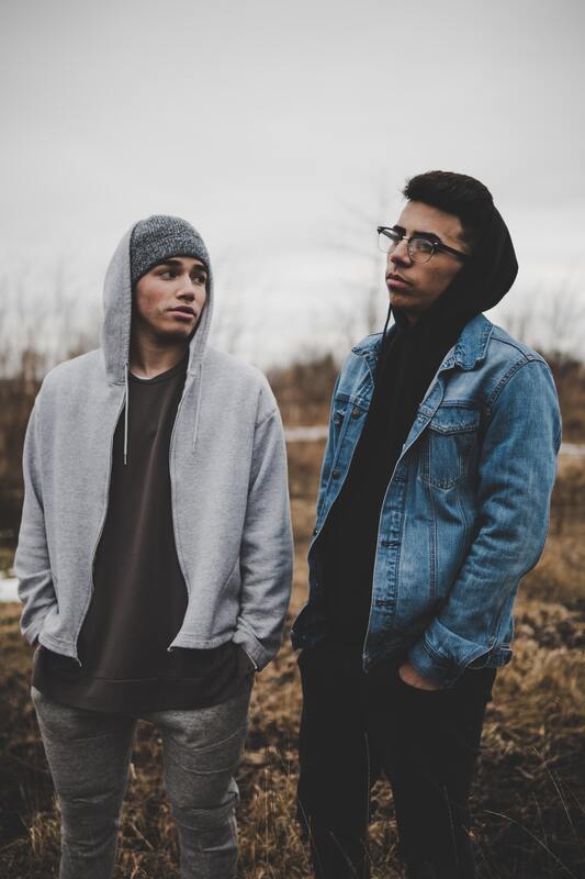 Two young men standing side by side representing that Maggie Jones Boyle offers individual therapy for young adults struggling with anxiety and low self-esteem.